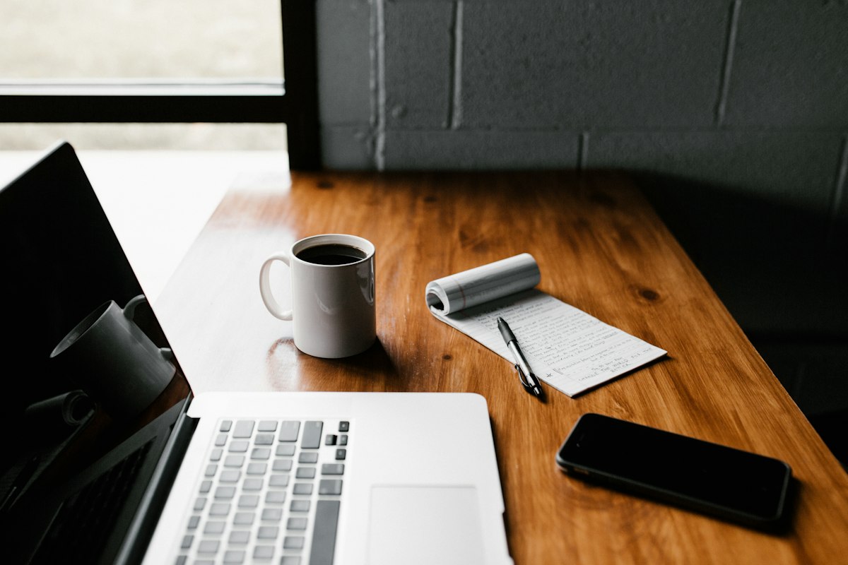 Calm desk with laptop, notepad and coffee